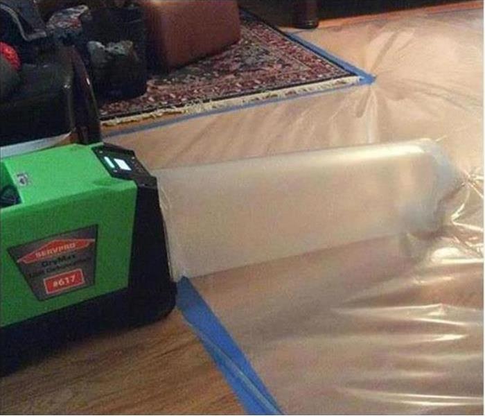 SERVPRO equipment connected to a plastic tube and plastic covering the floor
