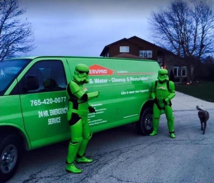 SERVPRO technicians dressed as superheroes standing in front of a SERVPRO van.