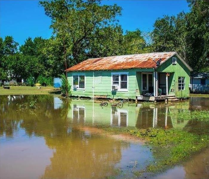A green home surrounded by standing water.   
